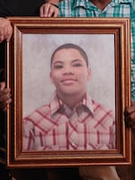 Bobbie and DeForrest hold a framed portrait of their son, Christian.