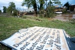 A sign commentating the flood of 1916 lies on the ground next to a flooded waterway near the Biltmore Village in the aftermath of Hurricane Helene on Sept. 28, 2024. 