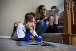 Ten-year-old Landon reads a book while his mother, Sarah McPartland, and sister, Vivian, read on the stairs at their home in Vancouver, Wa., Thursday, Feb. 28, 2019.