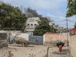 A woman reacts while walking in a street as smoke billows in the background from an explosive-laden car diffused by the Somali police in Mogadishu on Saturday.