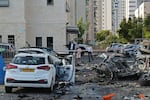 Residents walk past burnt-out vehicles in Ashkelon following a rocket attack from the Gaza Strip into Israel on Oct. 7, 2023.