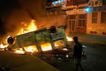 A boy stands next to a torched police vehicle as youth led protests calling for healthcare and education reforms turned violent, in Sale, Morocco, Wednesday, Oct. 1, 2025.