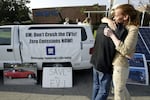 Chelsea Sexton hugs Paul Scott during a vigil held outside the General Motors Training Center in Burbank, Calif., protesting GM's plans to crush its EV1 electric vehicles located in the facility's parking lot.