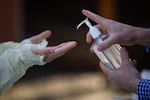 Oregon Health & Science University nurse practitioner Shelby Freed (left) sanitizes her hands between glove changes on Friday, March 20, 2020, in Portland, Ore. Testing for COVID-19 requires regular changing out of PPE like gloves, masks and gowns, but a nationwide shortage has prevented many health care workers from doing so.