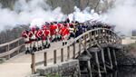 Minute Men and British reenactors fire a musket salute off the North Bridge at Minute Man National Historical Park.