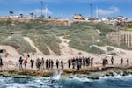 This aerial view shows members of security forces loyal to the interim Syrian government standing along a rocky beaech by Mediterranean sea coast in Syria's western city of Latakia on March 9.