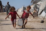 Displaced Palestinians girls carry a jerrycan after collecting water from a distribution point at a tent camp in Muwasi, an area that Israel has designated as a safe zone, in Khan Younis southern Gaza Strip, Monday, Sept. 29, 2025.