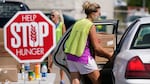 A volunteer loads a local resident's vehicle at a drive-up produce giveaway organized by a Des Moines food pantry on Aug. 28, 2020, in Des Moines, Iowa.