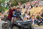 A rider from the Vampires soapbox team waves to the crowd on the back of the medical services ATV after crashing into hay bales on the side of the track.