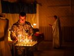 An Ukrainian serviceman of the 72nd Separate Mechanized Brigade, lights candles during a Christian Orthodox Easter religious service, in Donetsk region, Ukraine, Saturday, May 4, 2024.