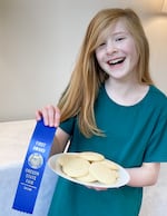 2024 Oregon State Fair Junior Baked Foods competition winner, Mary Foster, holding her blue ribbon and "Grandma Conrad's sugar cookies"