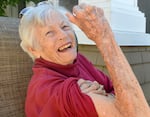 I. Riley Helmstetter, 102, smiles while flexing her arm in the style of "Rosie the Riveter," on June 11, 2026, in the courtyard of a senior living facility in Bend, Ore.