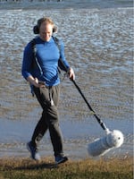 Chet Udell looks at his flashing metronome as he carries a boom microphone recording his footfalls and other environmental sound while he jogged around Newport, Ore., on Jan. 19, 2026.