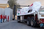 Egyptian Red Crecent members monitor trucks carrying humanitarian aid as they enter the Rafah crossing between Egypt and the Gaza Strip, following an agreement between Israel and Hamas on a ceasefire, Sunday, Oct. 12, 2025.