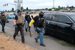 In this photo from August 2021, members of the far-right group Proud Boys surround a car they believe is driven by anti-fascist counter-protesters during clashes between the politically opposed groups in Portland, Ore. 