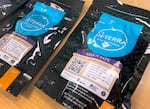 A close-up image of the black Deterra bags with the blue logo in the middle. A sticker on the bag includes a QR code for families to scan and get more information on safe disposal.