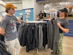 Ben Foster of Chattanooga, Tenn., (left) decides what he thinks about the tweed coat his friend Josh Elliott of Atlanta shows him. Elliott had heard about the Unclaimed Baggage store from a friend and was amazed by how organized it is.