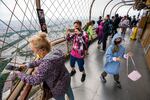 People look at a high-up view through a mesh fence.