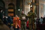 Soldiers and priests walk into the Church of the Most Holy Apostles Peter and Paul on Tuesday in downtown Lviv carrying a cross and an image of Ivan Koverznev, a Ukrainian lieutenant who was killed by Russian forces in March.