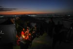 Reda Abu Zarada, 50, displaced from Jabaliya in nothern Gaza, sits by a fire with her grandchildren at a camp by the sea in Khan Younis, Gaza Strip, Thursday, Dec. 19, 2024.