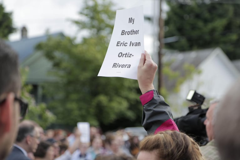 Audience members hoisted signs aloft as the names of victims were read aloud. The speaker also listed the victims' ages — many of them young — moving the audience to tears.
