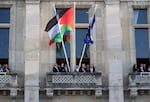 Officials wave after the Palestinian flag (center) has been set on the facade of the Saint-Denis city hall, outside Paris, Monday. France is helping organize efforts toward reviving a two-state solution to the Israeli-Palestinian conflict.