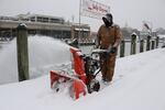 Tony Savage, who works for the city of Annapolis, clears snow along the City Dock in Annapolis, Md.