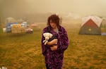 Shayanne Summers holds her dog Toph while wrapped in a blanket after several days of staying in a tent at an evacuation center at the Milwaukie-Portland Elks Lodge, Sunday, Sept. 13, 2020, in Oak Grove, Ore. "It's nice enough here you could almost think of this as camping and forget everything else, almost," said Summers about staying at the center after evacuating from near Molalla, Ore., which was threatened by the Riverside Fire.