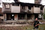 An armed resident walks past houses damaged during the Oct. 7 attack by Hamas militants in Kibbutz Kissufim in southern Israel on Nov. 20, 2023, amid the ongoing battles between Israel and the Hamas.