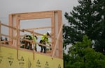 Two construction workers add in wood panels at the Modera Woodstock construction site in Southeast Portland on July 7, 2023. Designed by Leeb Architects, the multi-use building will provide 194 housing units and around 6,000 square feet of retail space.