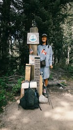 Pacific Crest Trail hiker Derek Hu of Taiwan stands next to a hiker-built trail monument on Aug. 11, 2026, near Rainy Pass, Washington.