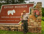 Brian Gibbs, pictured with his son Oliver in front of the Effigy Mounds National Monument park sign, in July 2024.