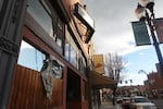 A ripped tarp hangs over a window of a vacant bar.