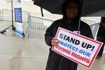 A demonstrator holds an umbrella and a sign saying “STAND UP! PROTECT OUR VOTING RIGHTS” outside the U.S. Supreme Court in March in Washington, D.C.