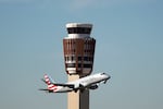 An American Eagle jet flies past the air traffic control tower at Phoenix Sky Harbor International Airport on, Nov. 8, 2025. As essential employees, controllers were required to work during the government shutdown without pay. When the last shutdown ended in 2019, it took some years to get all the money they were owed.
