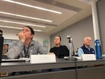 Three people sitting at a conference table.