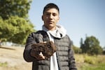 Woodburn High School student Jairo Aguirre holds up a chunk of soil containing bog beans. Bog beans are relics of a cold-weather marsh plant that's found in Canada and Alaska today, and hasn't been seen in Oregon since the Ice Age.