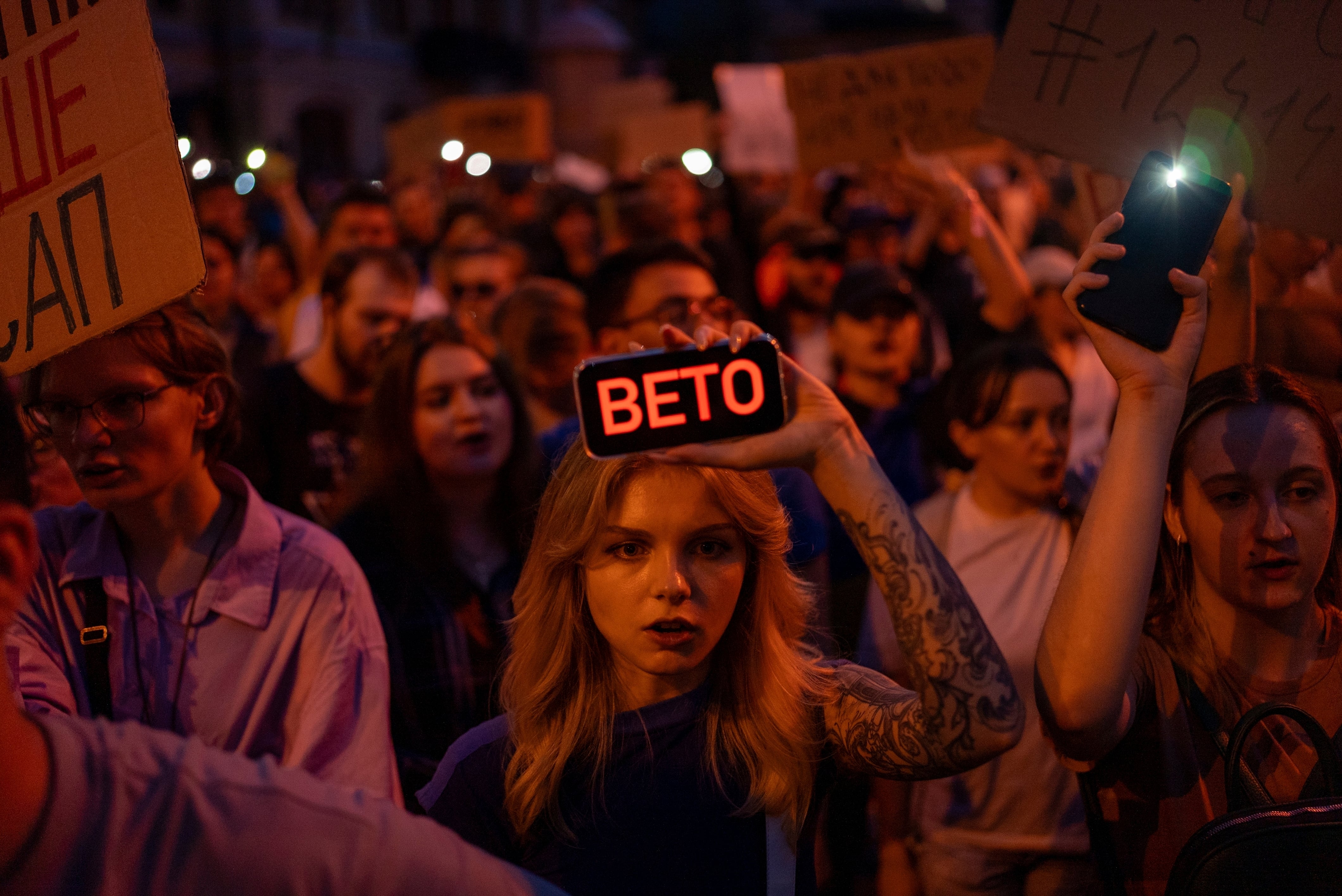 A woman holds a phone with a sign reads