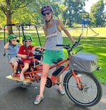 In this supplied photo, Melissa Kostelecky poses on her bike on July 8, 2024, with her children, Athena and Odin.