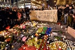 FILE - In this March 22, 2016 file photo people holding a banner reading "I am Brussels" behind flowers and candles to mourn for the victims at Place de la Bourse in the center of Brussels. Bombs exploded at the Brussels airport and one of the city's metro stations Tuesday, killing and wounding scores of people, as a European capital was again locked down amid heightened security threats.