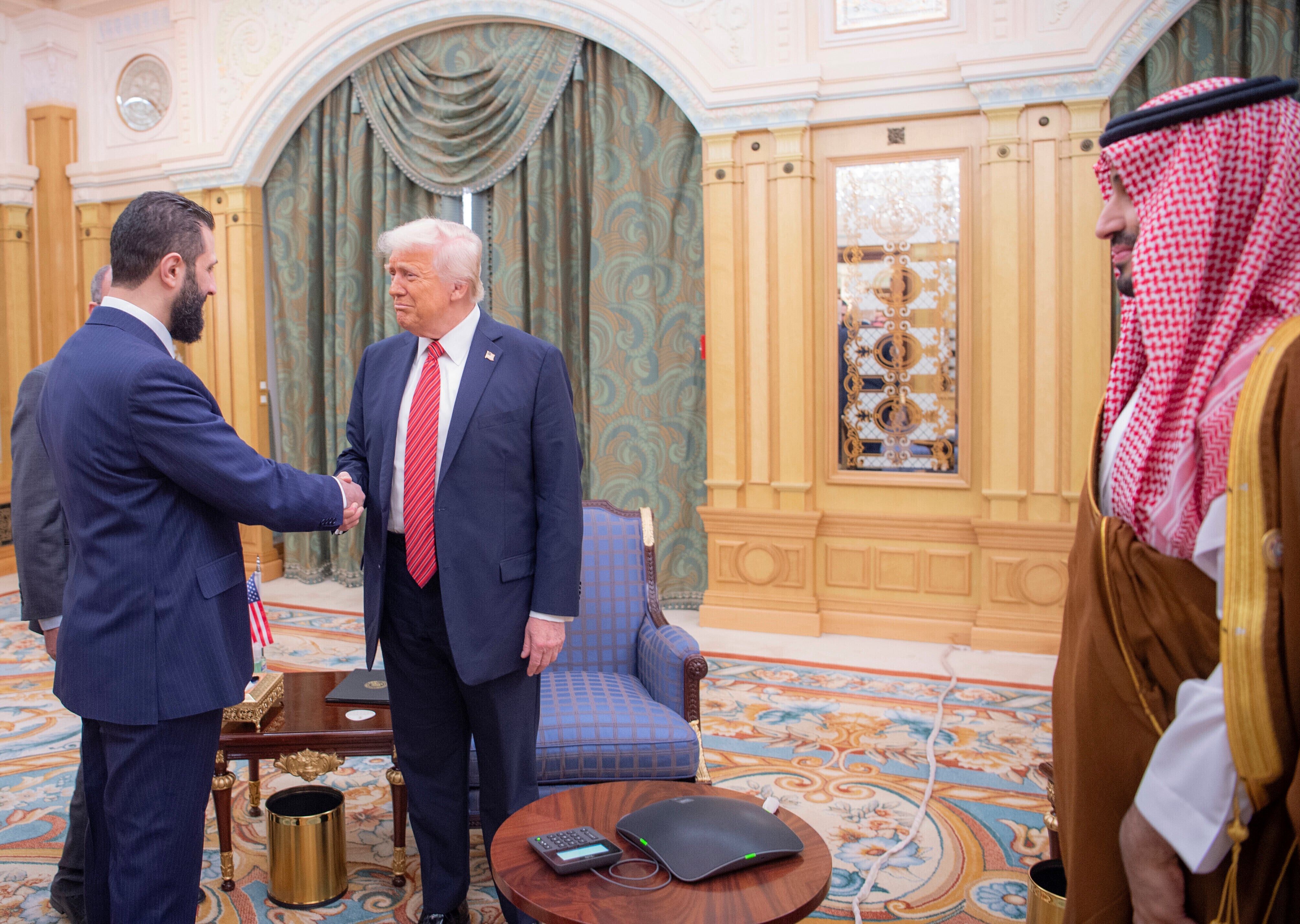 In this photo released by the Saudi Royal Palace, interim Syrian President Ahmad al-Sharaa shakes hands with U.S. President Donald Trump in Riyadh, Saudi Arabia, Wednesday, May 14, 2025. At right is Saudi Crown Prince Mohammed bin Salman. (Bandar Aljaloud/Saudi Royal Palace via AP)