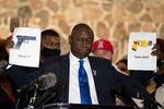 FILE - In this Thursday, April 15, 2021 file photo, attorney Ben Crump, representing the family of Daunte Wright, holds up images depicting an X26P Taser and a Glock 17 handgun during a news conference at New Salem Missionary Baptist Church in Minneapolis.