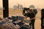 In this Sept. 8, 2020, file photo Jonathan Thompson of the Keizer, Ore., Chamber of Commerce delivers donated bottled water to the Oregon State Fairgrounds in Salem, which is now an evacuation center as wildfires threaten towns in Oregon.