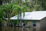 In a flooded Valrico neighborhood a man waits outside of a home after paddle two others, who entered through the window, up to it.