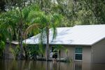 In a flooded Valrico neighborhood a man waits outside of a home after paddle two others, who entered through the window, up to it. 