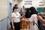 Pass the Mic mentor Courtney Sheedy, left, gives Linh Doan an acoustic guitar to take home at the workshop in Portland, Ore., Friday, Aug. 2, 2019. Instrument drives from community supporters allowed Pass the Mic students to keep their instruments for free.