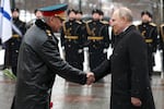 Russian President Vladimir Putin, right, shakes hands with Russian Defense Minister Sergei Shoigu as they arrive to take part in a wreath laying ceremony at the Tomb of the Unknown Soldier in Alexander Garden on Defender of the Fatherland Day, in Moscow, Russia, on Friday.