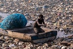 Old Fadama, Accra, Ghana, February 8, 2023. Holding onto a water pipe, McCoy pulls his canoe towards the banks to recover more recyclable plastics.