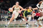 FILE - Indiana Fever guard Caitlin Clark (22) drives as Seattle Storm guard Nika Muhl defends during the second half of a WNBA basketball game, Wednesday, May 22, 2024, in Seattle.