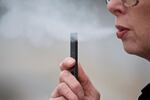 Chantel Williams exhales a puff of vapor from a Juul pen in Vancouver, Wash., Tuesday, April 16, 2019. Juul Labs is expected to pay the state of Oregon more than $20 million in a settlement. (AP Photo/Craig Mitchelldyer)